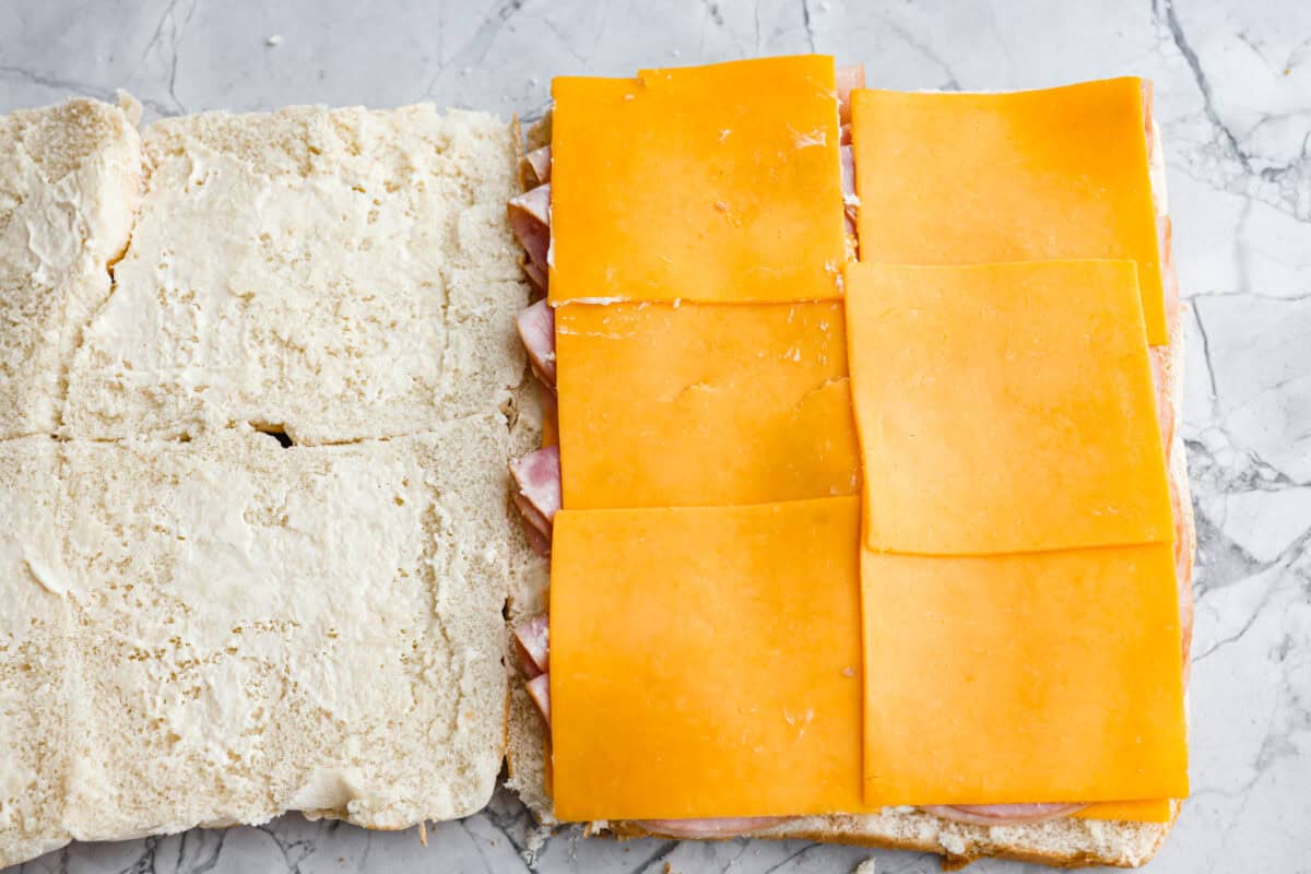 Ham and cheese are a match made in heaven! Add sweet Hawaiian rolls, topped with an incredible glaze, and you've got something magical! These Ham and Cheese sliders are super easy and insanely delicious! A second layer of cheese on top of the ham.