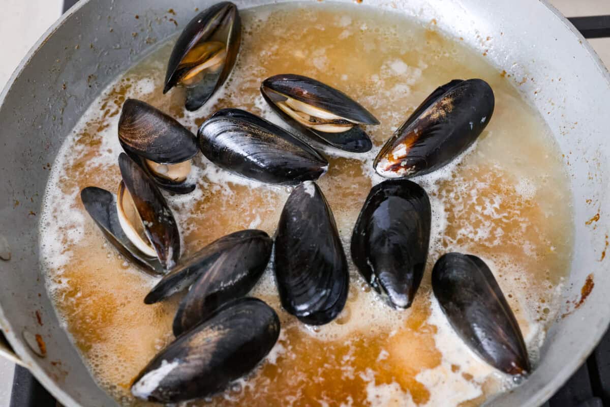 My seafood pasta has a silky lemon garlic cream sauce that is to die for! It's loaded with tender shrimp, scallops, and mussels. Itโs the perfect date night dish! Muscles cooking in pasta water and butter.