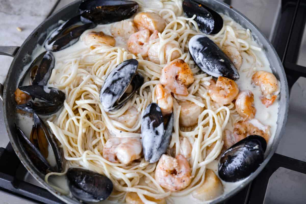 My seafood pasta has a silky lemon garlic cream sauce that is to die for! It's loaded with tender shrimp, scallops, and mussels. Itโs the perfect date night dish! Cooked shrimp, scallops and muscled added to the sauce with the noodles.