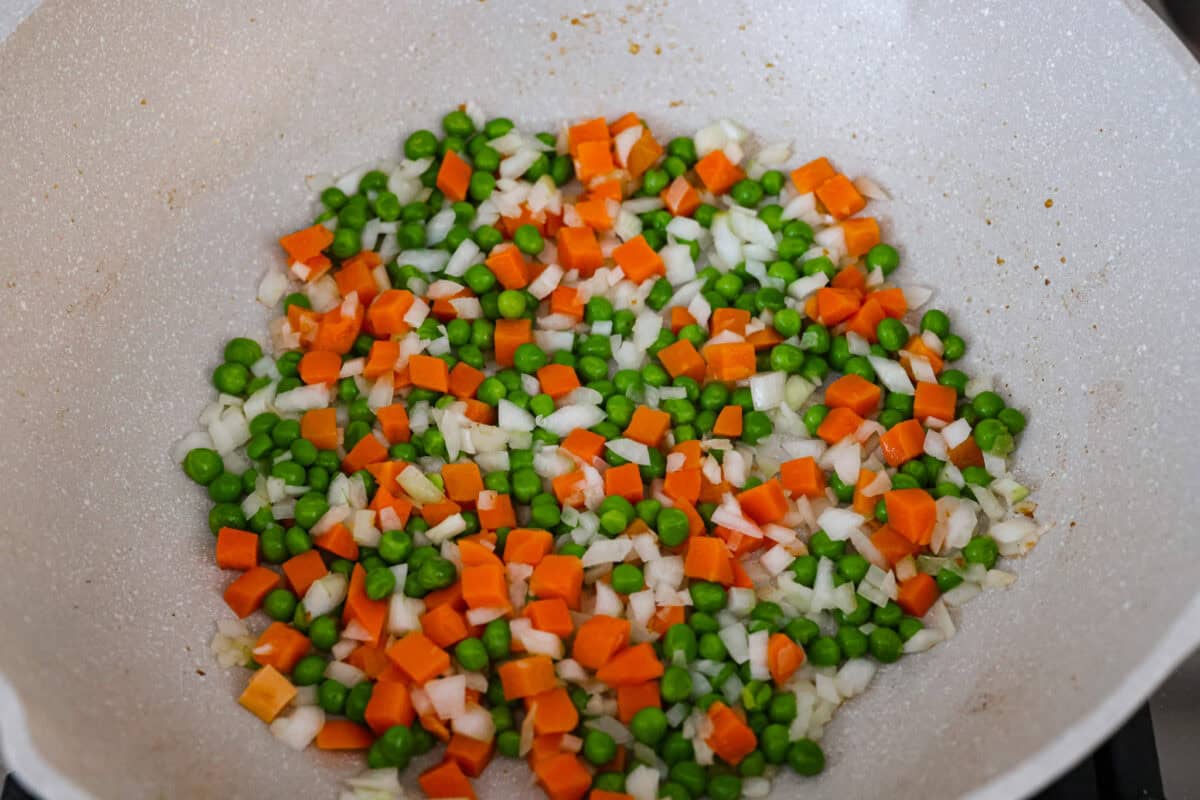 Skip the takeout! This shrimp fried rice is faster, fresher, and way more flavorful! Juicy shrimp, tender veggies, fluffy rice, and scrambled eggs all come together in one irresistible skillet meal. Veggies cooking in a skillet.