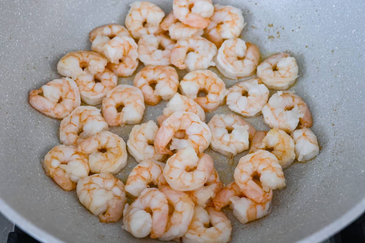 Skip the takeout! This shrimp fried rice is faster, fresher, and way more flavorful! Juicy shrimp, tender veggies, fluffy rice, and scrambled eggs all come together in one irresistible skillet meal. Shrimp cooking in a skillet.