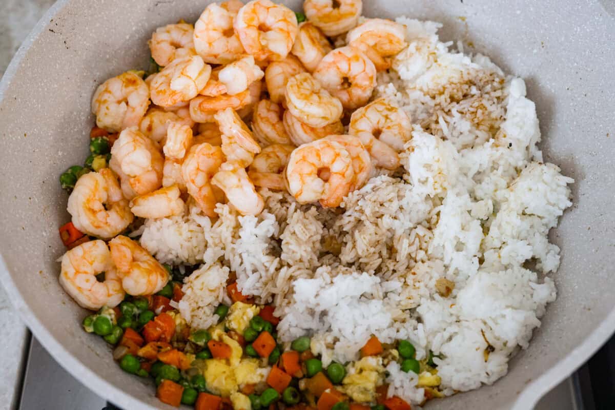 Skip the takeout! This shrimp fried rice is faster, fresher, and way more flavorful! Juicy shrimp, tender veggies, fluffy rice, and scrambled eggs all come together in one irresistible skillet meal. Rice, shrimp, sauce, and seasonings added to the skillet with the veggies and shrimp.