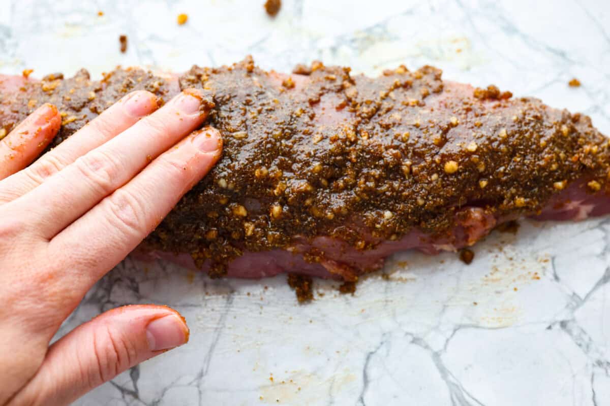 Air fryer pork tenderloin is the ultimate weeknight dinner hero! It's quick, juicy, and packed with flavor! It cooks up perfectly with minimal effort, thanks to a simple marinade and the magic of the air fryer. Olive oil added to the spice rub and someone is spreading it on the pork tenderloin.