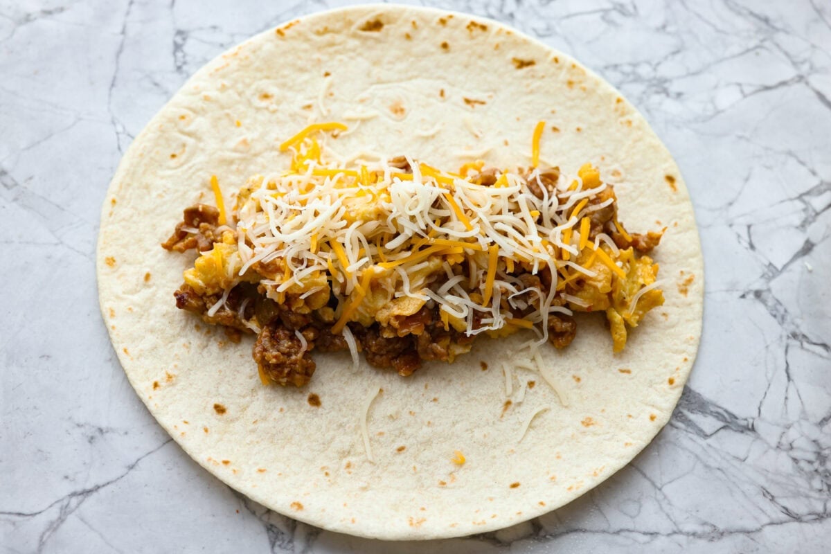My easy breakfast enchiladas are packed with sausage, fluffy eggs, and zesty salsa, then smothered in a rich, creamy sauce that puts every other breakfast to shame. You can even make them ahead! Tortilla with some of the sausage and egg mixture in the middle with some cheese over the top.