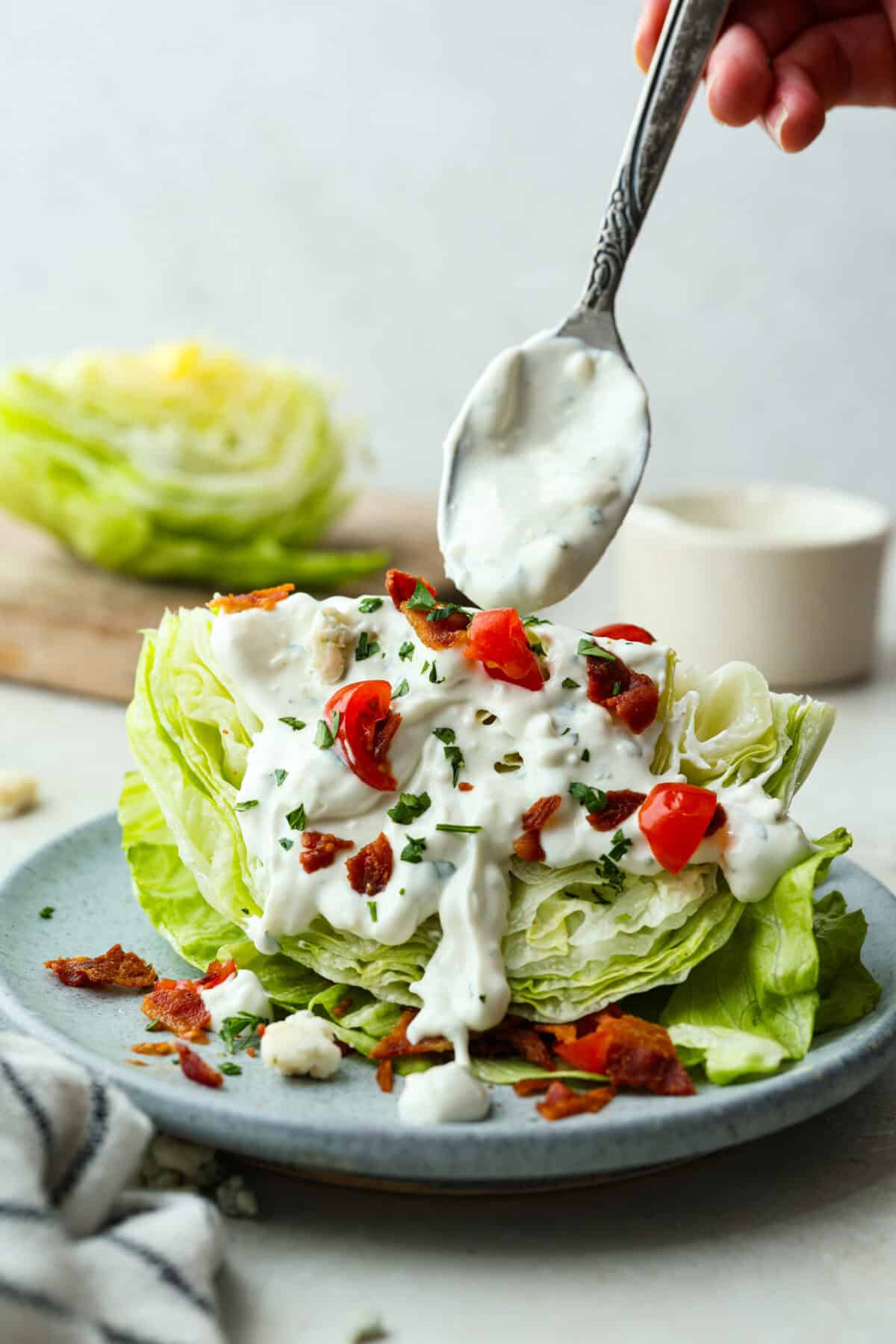 Once you try this homemade blue cheese dressing, thereโs no going back to store-bought! Itโs the perfect cool and creamy drizzle for wings, salads, and more. Someone spooning blue cheese dressing over a wedge salad.