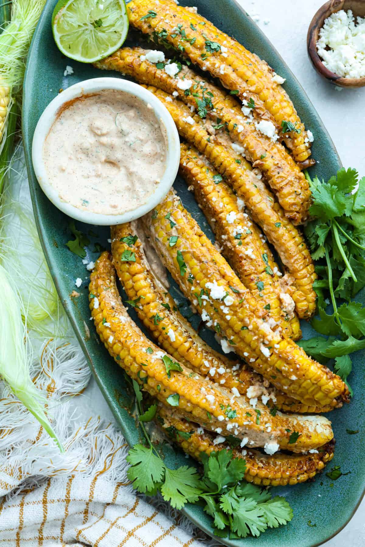 I had to try these viral Corn Ribs, and now I totally get the hype! They're fun, handheld, and smothered in creamy, zesty Mexican street corn flavor. Make a batch to share... or donโt. I wonโt judge. Serving platter with cooked corn ribs smothered in Elotรฉ sauce and garnished with Cotija cheese and cilantro.