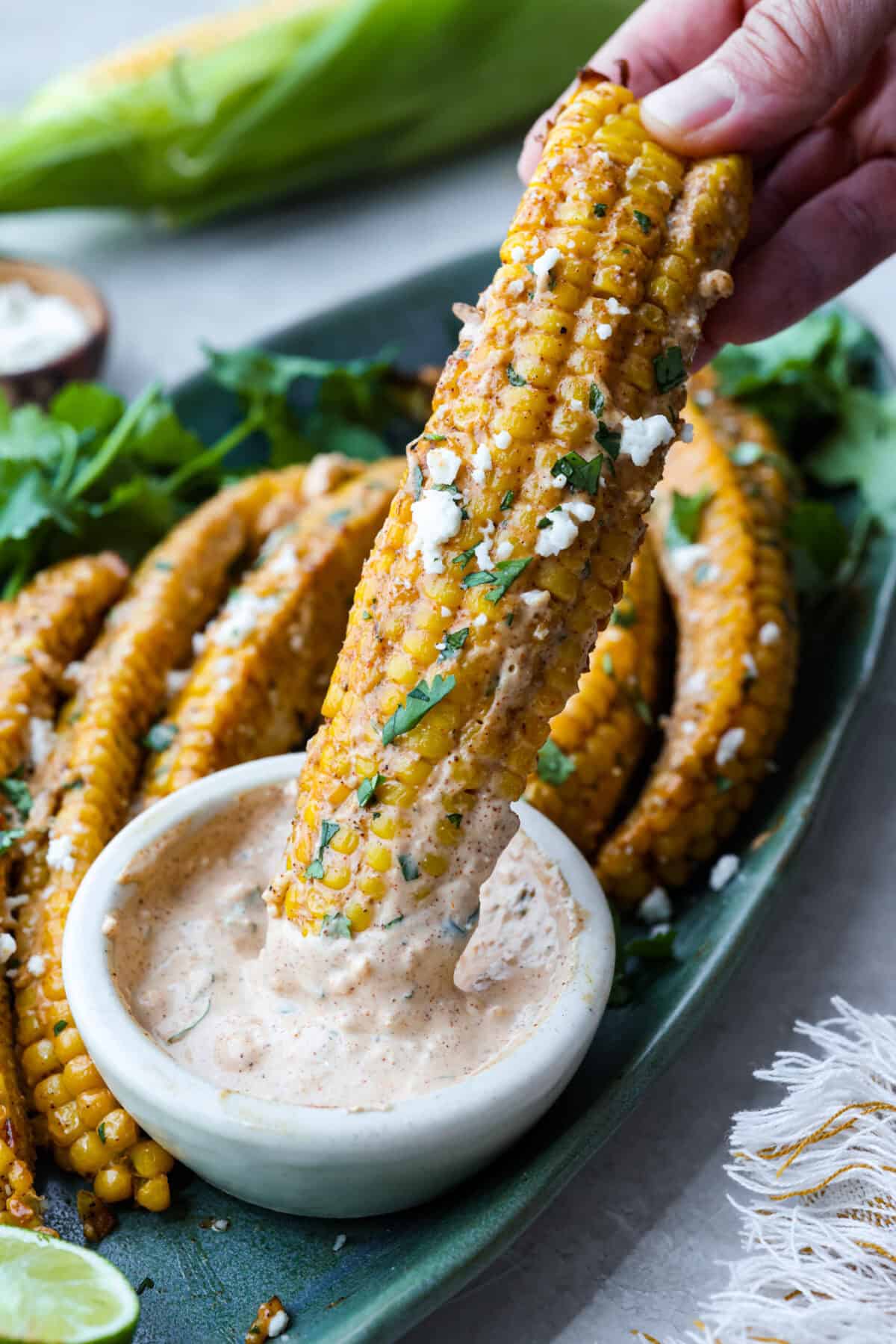 I had to try these viral Corn Ribs, and now I totally get the hype! They're fun, handheld, and smothered in creamy, zesty Mexican street corn flavor. Make a batch to share... or donโt. I wonโt judge. Someone dipping a corn rib into the elote sauce.
