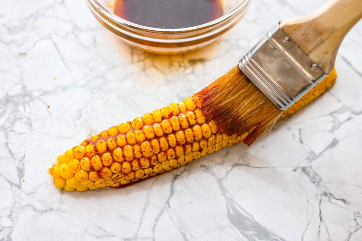 I had to try these viral Corn Ribs, and now I totally get the hype! They're fun, handheld, and smothered in creamy, zesty Mexican street corn flavor. Make a batch to share... or donโt. I wonโt judge. Someone brushing the corn rib with marinade.
