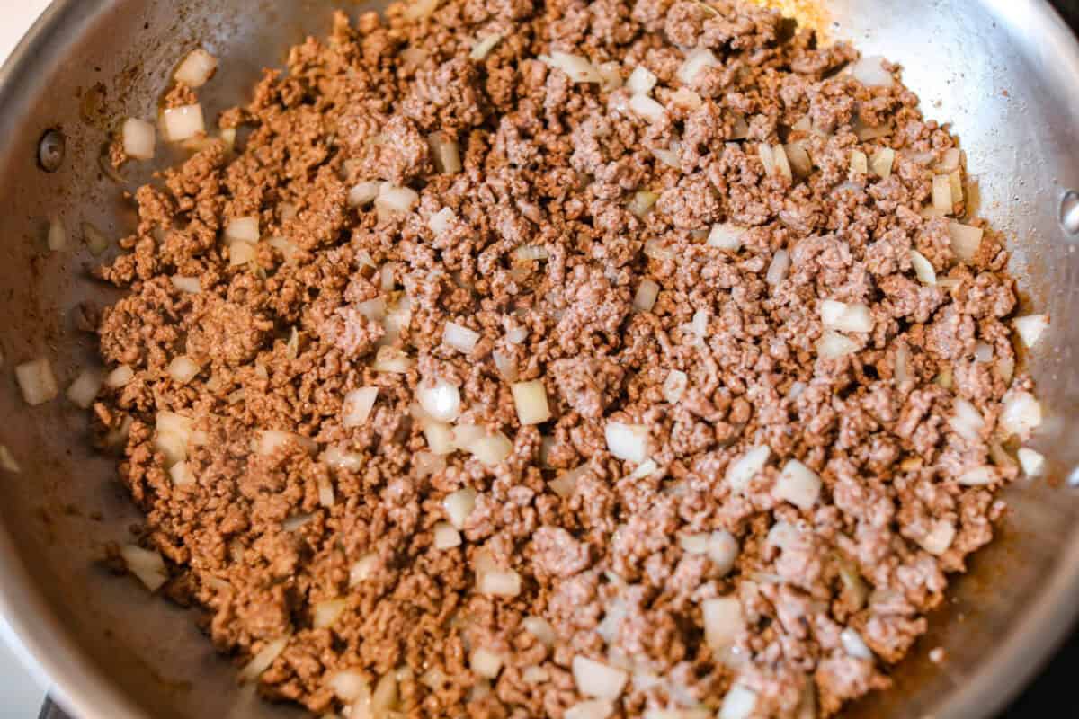 Crockpot million dollar pasta is rich, creamy, and straight-up dreamy. No boiling, no babysitting, just toss it all in and let your slow cooker work its magic! Ground beef and onions being cooked in a skillet.