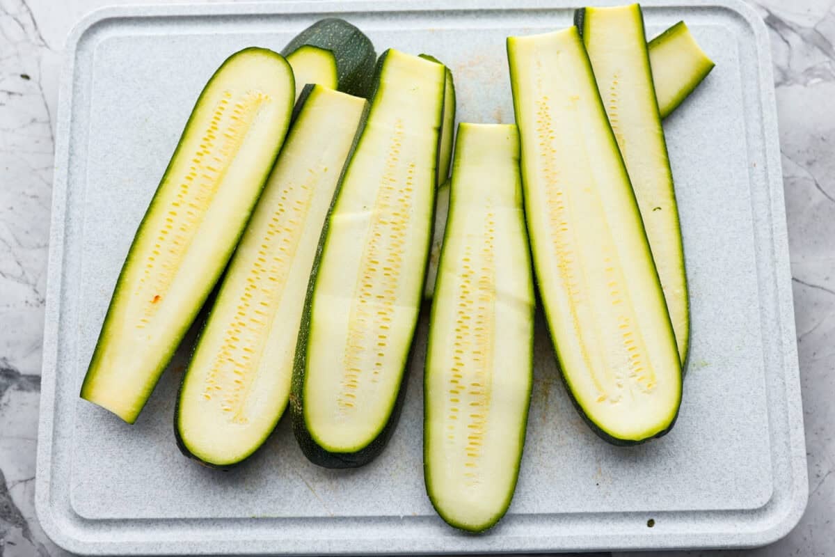 If you're not making zucchini bread with all of that home-grown zucchini, then you HAVE to try this grilled zucchini! Light, smoky, and perfectly seasoned, it cooks up in minutes and goes with just about everything. ZUcchini sliced on a cutting board.