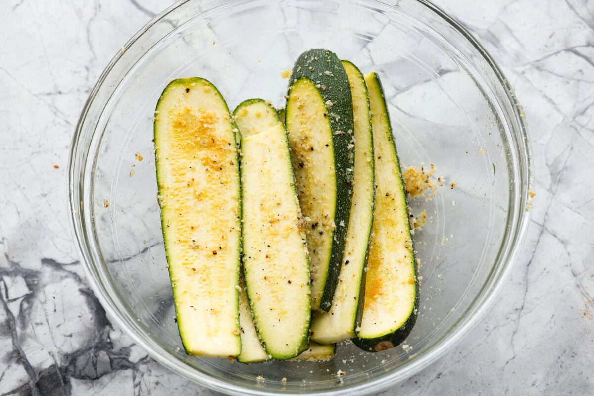 If you're not making zucchini bread with all of that home-grown zucchini, then you HAVE to try this grilled zucchini! Light, smoky, and perfectly seasoned, it cooks up in minutes and goes with just about everything. All of the zucchin slices covered in cheese and seasonings.