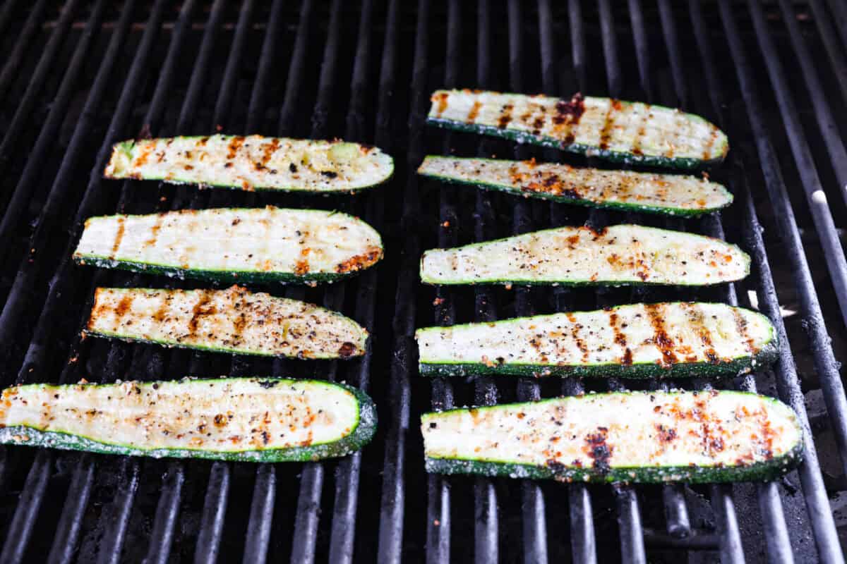 If you're not making zucchini bread with all of that home-grown zucchini, then you HAVE to try this grilled zucchini! Light, smoky, and perfectly seasoned, it cooks up in minutes and goes with just about everything. Char grill marks on the top of the slices that are cooking on the grill.