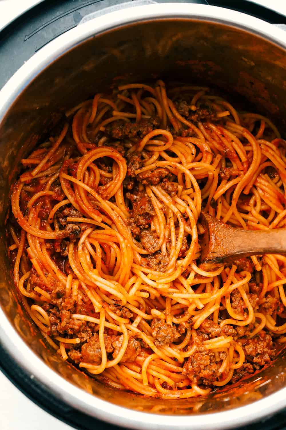 When dinner needs to happen fast, instant pot spaghetti is your new best friend! Perfectly seasoned beef, tender pasta, and a rich, saucy finish, all in one pot and ready in less than 15 minutes. Someone stirring all of the cooked ingredients together in the instant pot.