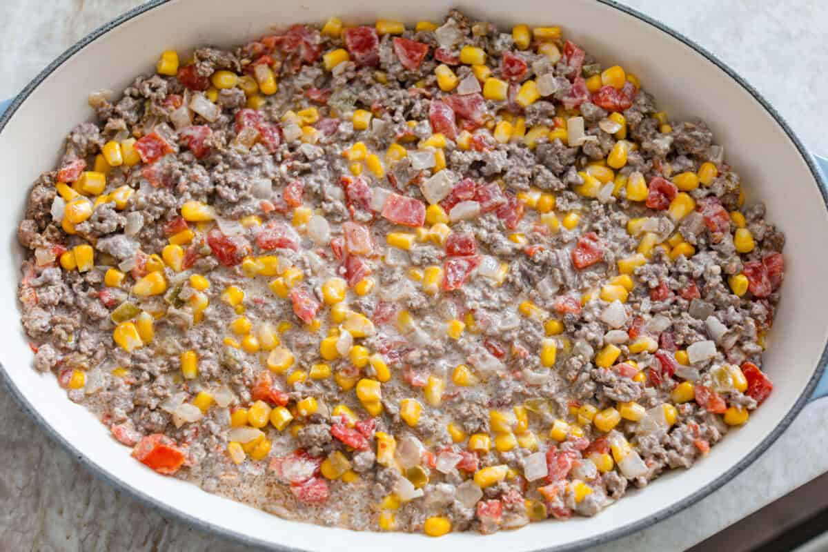 Cowboy casserole is my ultimate mom hack. Beef, cheese, corn, and tater tots, whatโs not to love? Even the picky eaters mysteriously forget how to be picky. Ground beef mixture all mixed together and added to the bottom of the baking dish.