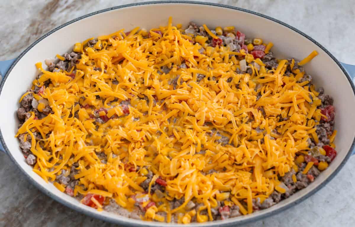 Cowboy casserole is my ultimate mom hack. Beef, cheese, corn, and tater tots, whatโs not to love? Even the picky eaters mysteriously forget how to be picky. Cheese spread over the tope of the ground beef mixture.