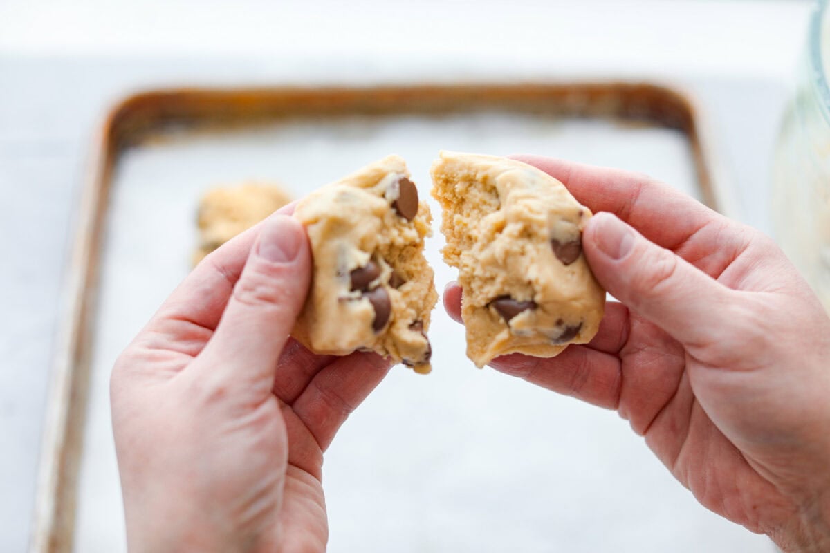 These copycat Crumbl cookies are HUGE, buttery, and loaded with melty chocolate chips. Fresh out of the oven, they just might be even better than the real deal. Bake a batch, do a taste test, and let me know if you like these better! Someone tearing a ball of cookie dough in half.