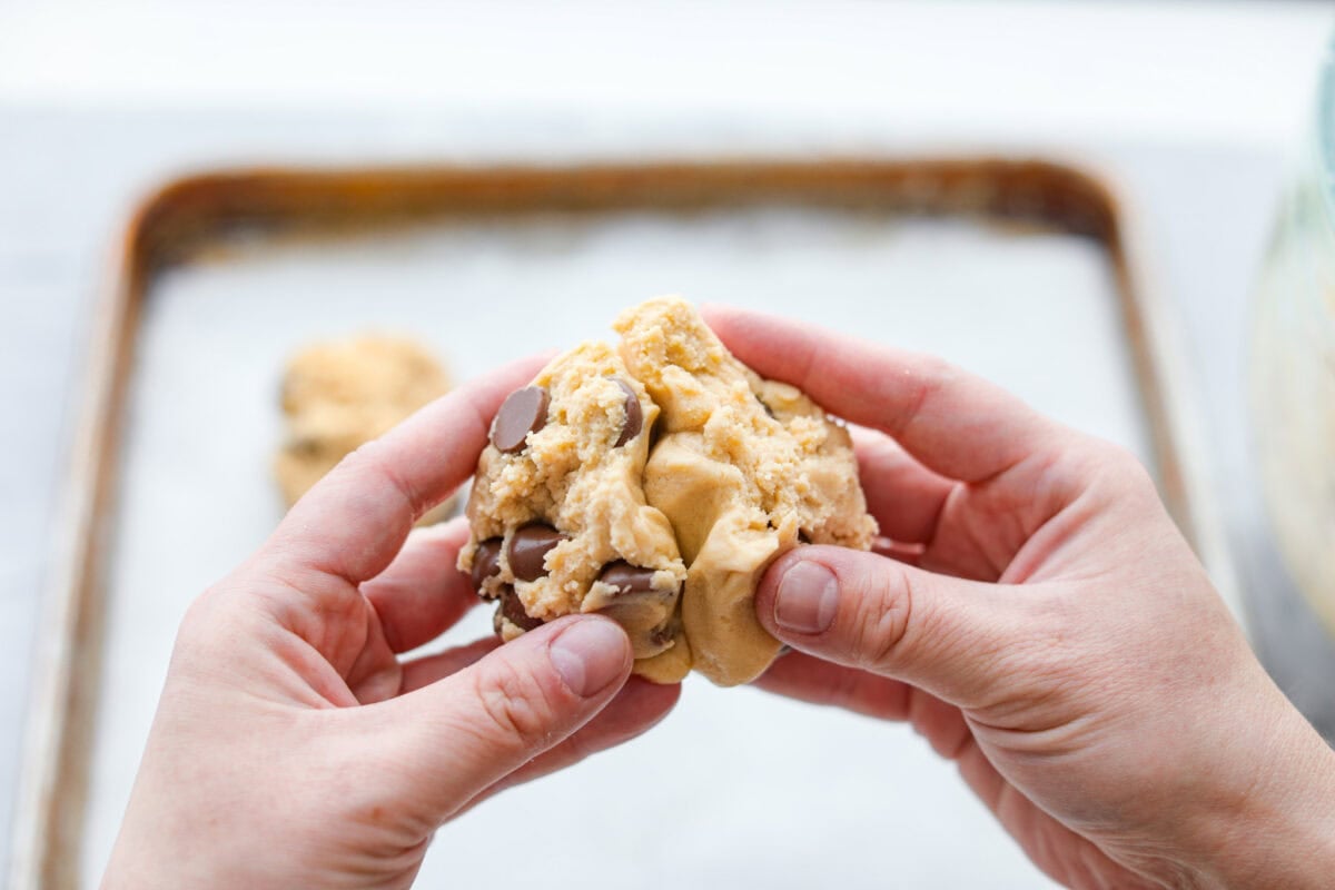 These copycat Crumbl cookies are HUGE, buttery, and loaded with melty chocolate chips. Fresh out of the oven, they just might be even better than the real deal. Bake a batch, do a taste test, and let me know if you like these better! Someone smashing the halves of dough back together.