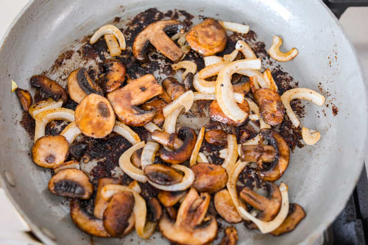 Cube steaks are my go-to budget comfort food. They're quick, cozy, and smothered in gravy. I love them with mashed potatoes or veggies, and I’ve got a simple trick to keep them melt-in-your-mouth tender every time. Mushrooms and onions cooking in a skillet.