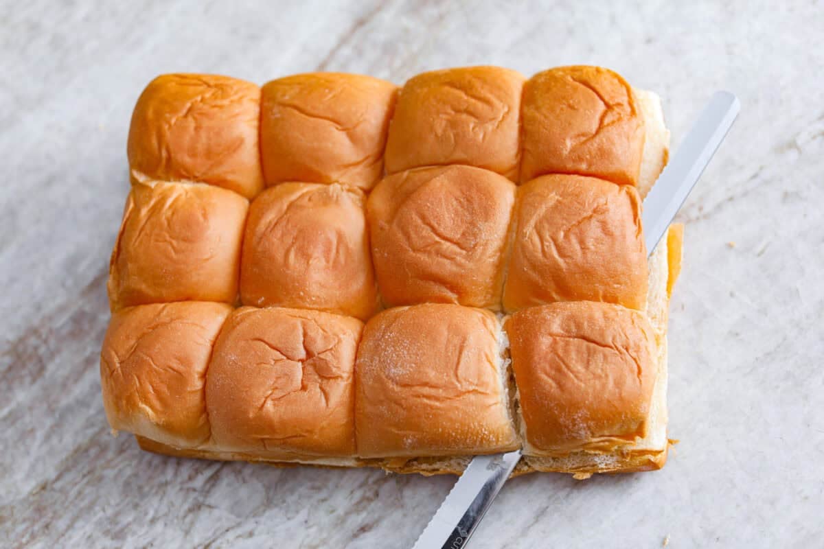 Sometimes you just need warm, gooey cinnamon rolls without the hours of waiting. These Hawaiian Roll Cinnamon Rolls are the cozy little hack that brings all the cinnamon-sugar joy with half the effort. The top half of the Hawaiian rolls being cut off.