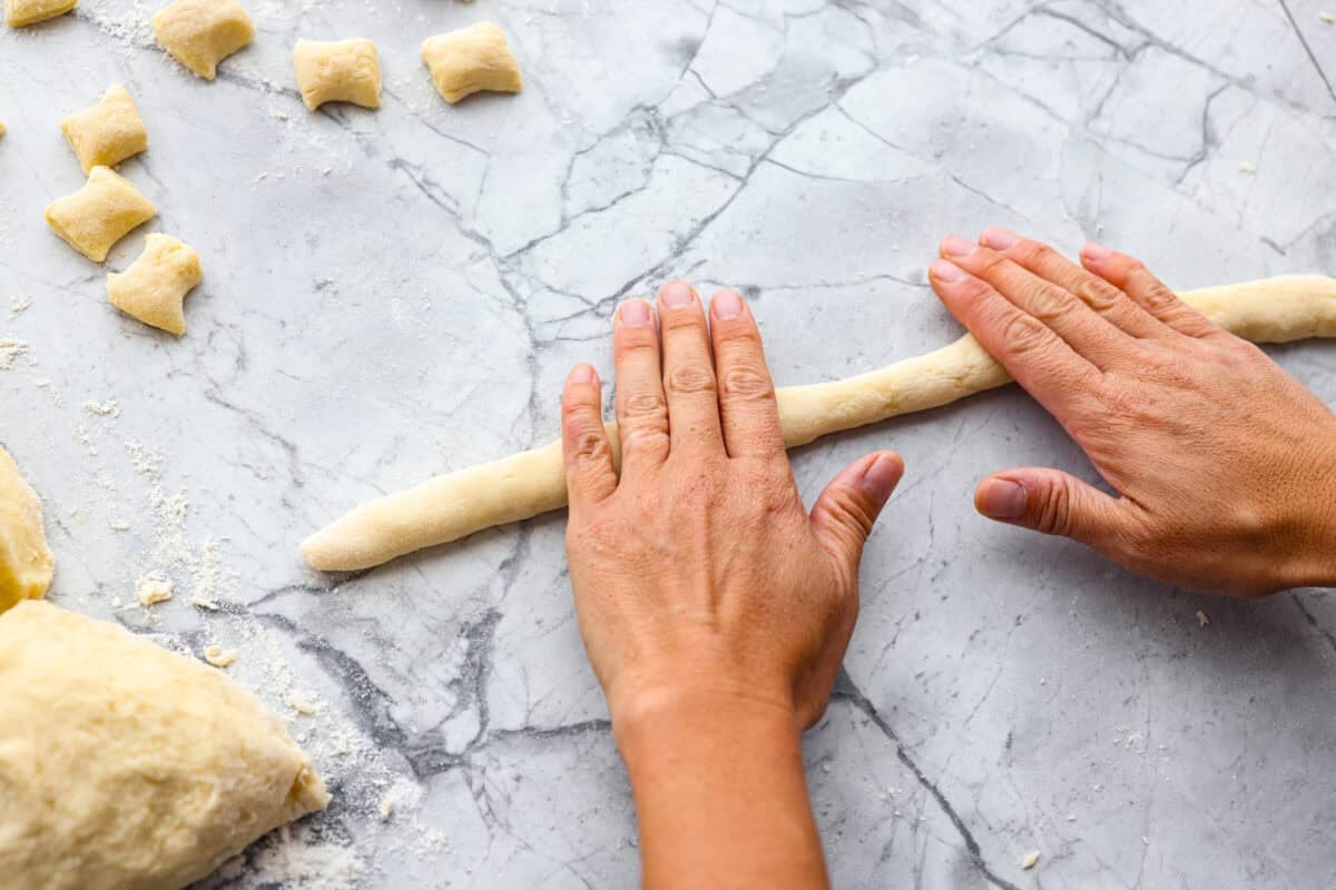 Homemade potato gnocchi is easier than you think! With just 5 simple ingredients, you can make soft, pillowy gnocchi at home. I’ll walk you through each step with clear instructions so you can master this classic Italian recipe on your first try. Someone rolling out dough into strips/snakes.