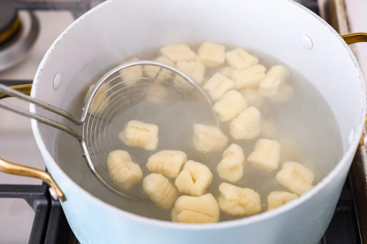 Homemade potato gnocchi is easier than you think! With just 5 simple ingredients, you can make soft, pillowy gnocchi at home. I’ll walk you through each step with clear instructions so you can master this classic Italian recipe on your first try. Pot of water with cooked gnocchi pieces.