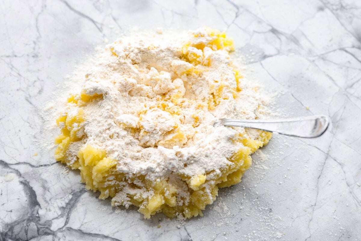 Homemade potato gnocchi is easier than you think! With just 5 simple ingredients, you can make soft, pillowy gnocchi at home. I’ll walk you through each step with clear instructions so you can master this classic Italian recipe on your first try. Someone mixing mashed potatoes with flour, egg, and salt.