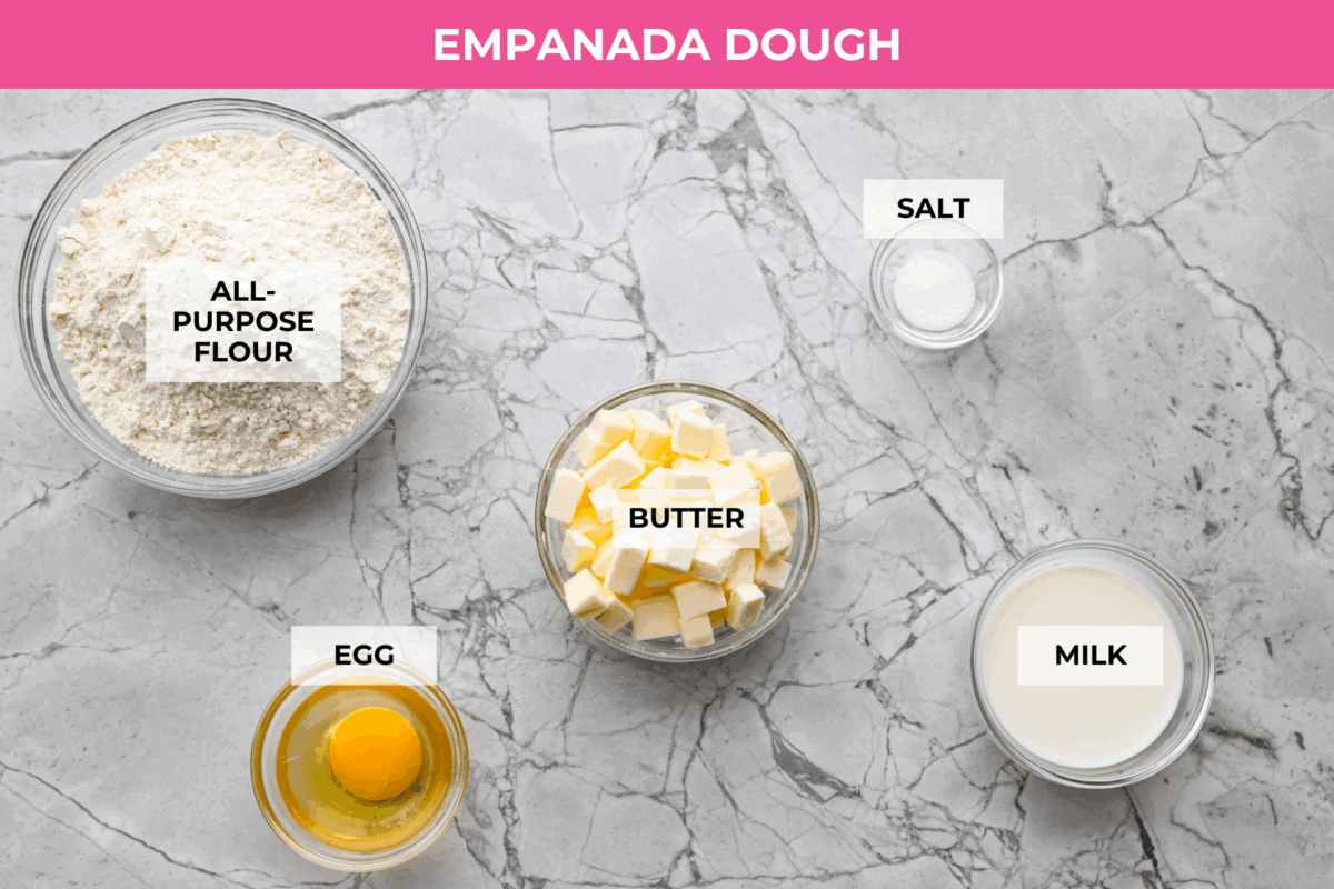 Okay, I just made homemade empanadas and Iโm obsessed! Crispy golden pockets stuffed with beef, potatoes, peas, and all the Mexican spices. You seriously need these in your life. Overhead shot of labeled empanada dough ingredients.