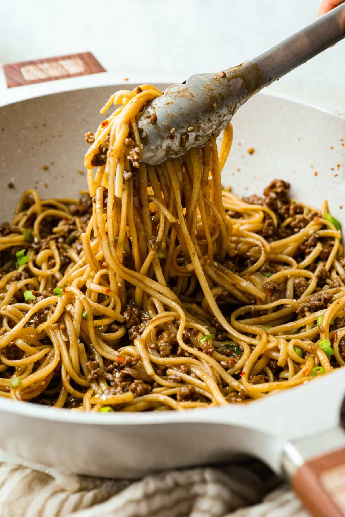 You guys are obsessed with my Korean Ground Beef rice bowls, so I decided I needed a noodle version. Tender beef, savory goodness, and those irresistible Korean flavors all wrapped up in one slurp-worthy Korean Beef Noodle dish. Someone lifting a portion of the Korean beef noodles out of the pan.
