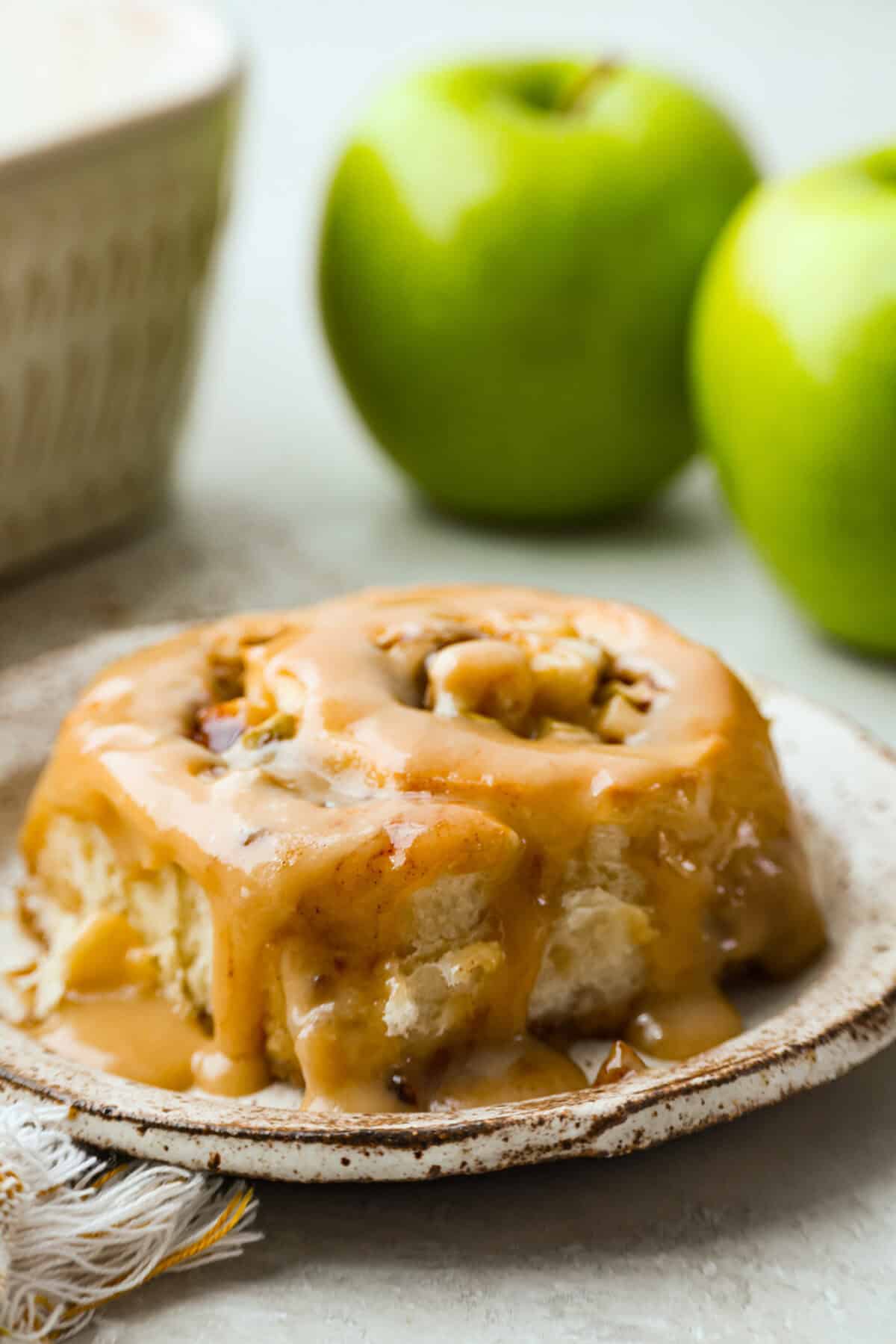 Single caramel apple cinnamon roll on a plate. 