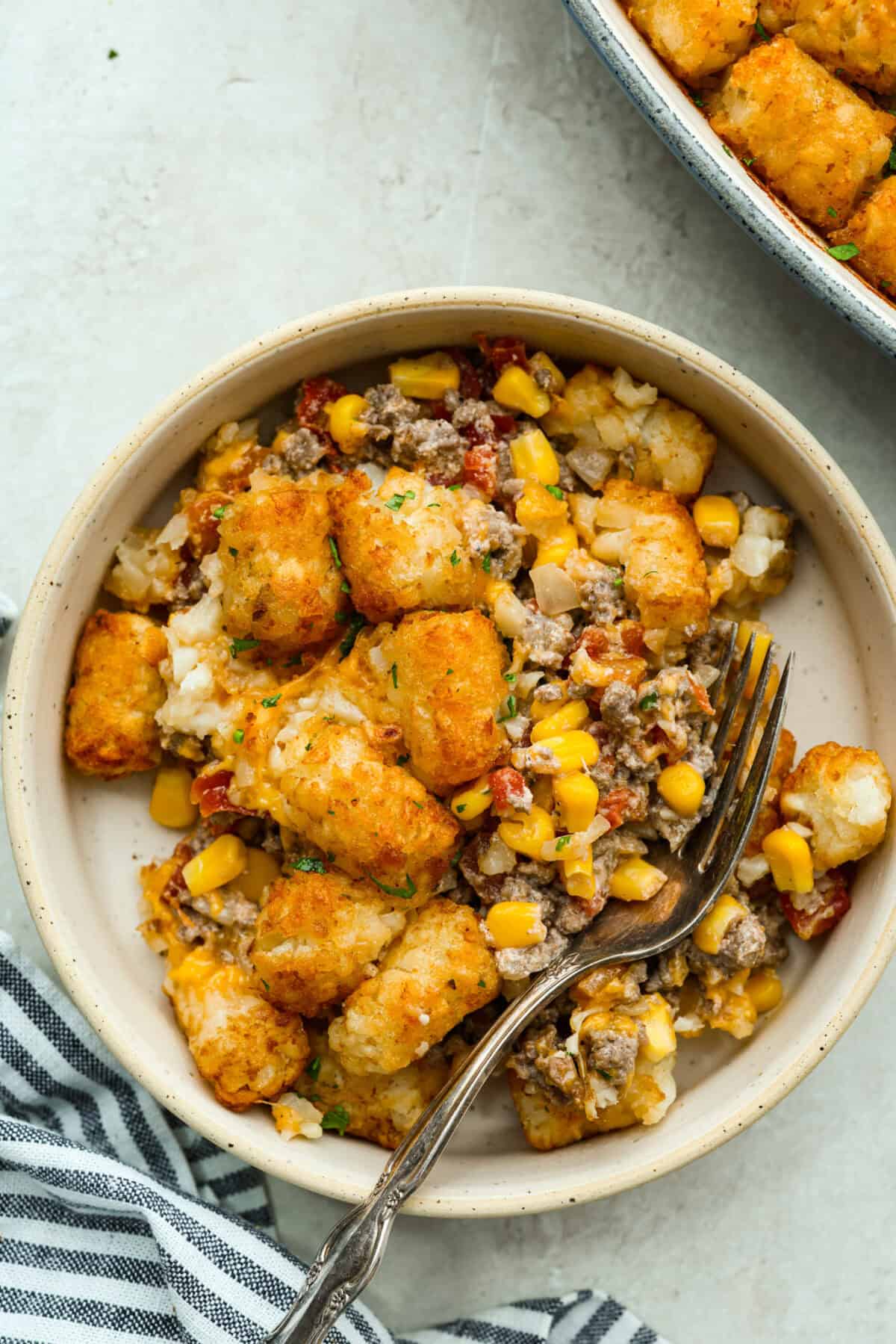 Cowboy casserole is my ultimate mom hack. Beef, cheese, corn, and tater tots, whatโs not to love? Even the picky eaters mysteriously forget how to be picky. Plated portion of cowboy casserole.