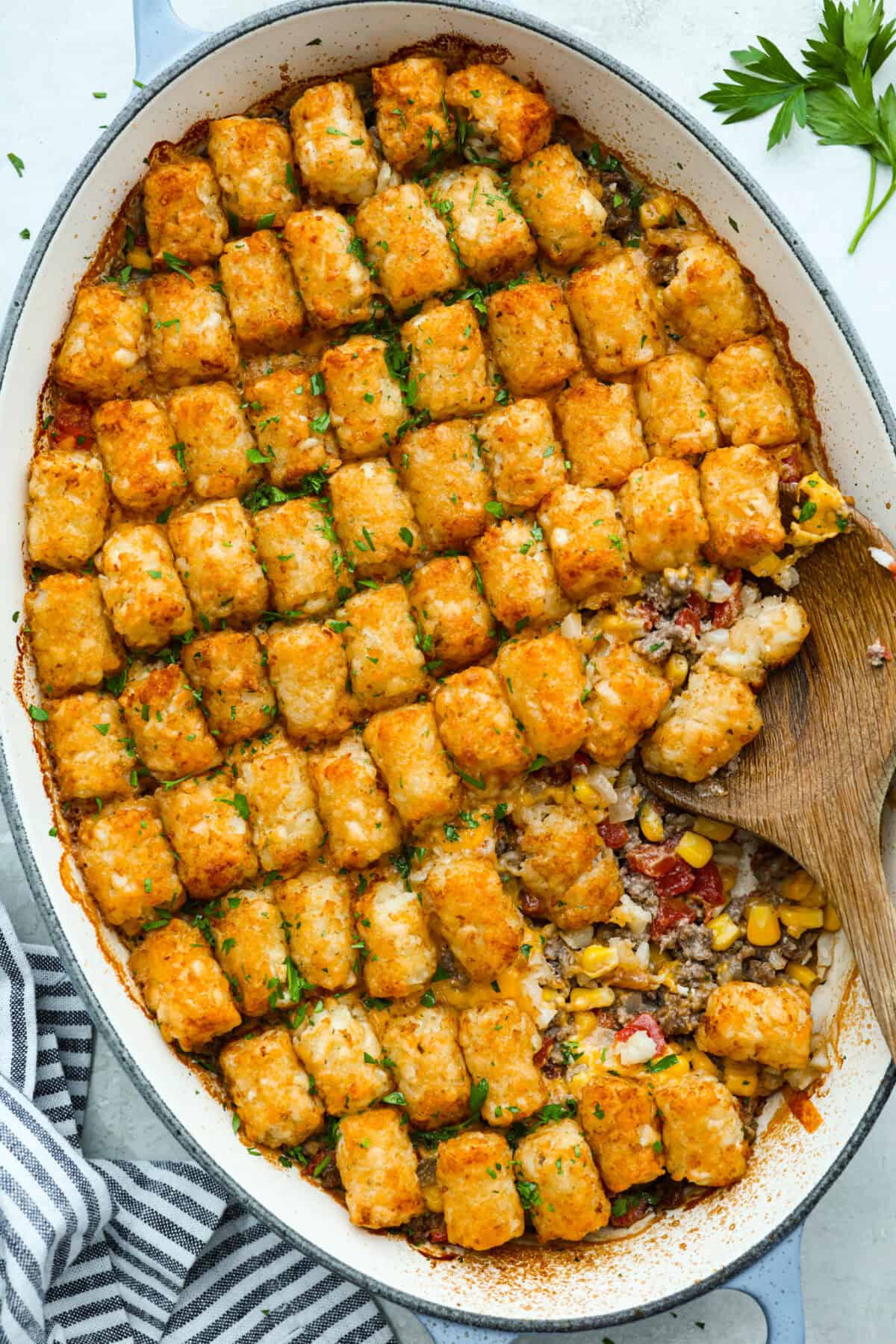 Cowboy casserole is my ultimate mom hack. Beef, cheese, corn, and tater tots, whatโs not to love? Even the picky eaters mysteriously forget how to be picky. Overhead shot of baked cowboy casserole in the baking dish.