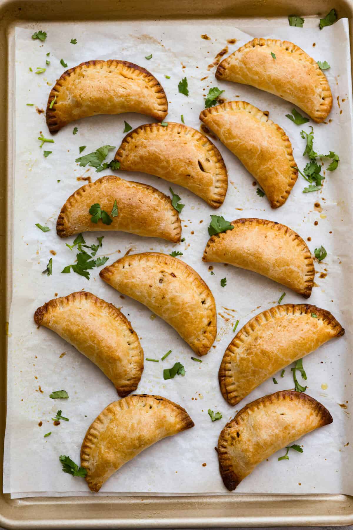 Okay, I just made homemade empanadas and Iโm obsessed! Crispy golden pockets stuffed with beef, potatoes, peas, and all the Mexican spices. You seriously need these in your life. Baked empanadas on a baking sheet.