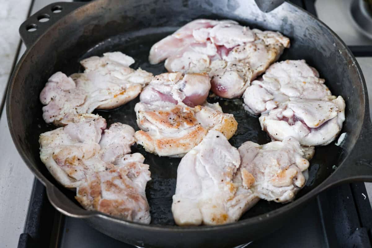 Sweet, savory, and full of summer vibes, peach chicken bakes up juicy and golden in a buttery peach preserve sauce with fresh peaches, Dijon, and a hint of garlic. Finished with basil, it’s simple, elegant, and packed with flavor! Chicken thighs cooking in a skillet.