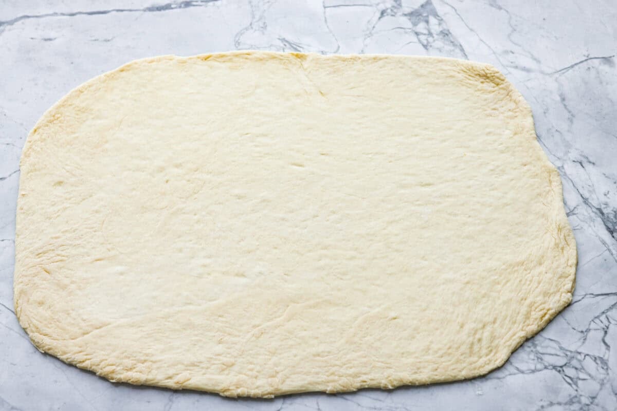 I just threw these pepperoni pizza rolls together in like 20 minutes, and my kids demolished them. AND they helped make them! You guys need to save this for a fast, fun snack or easy dinner! Pizza Dough rolled out into a rectangle.