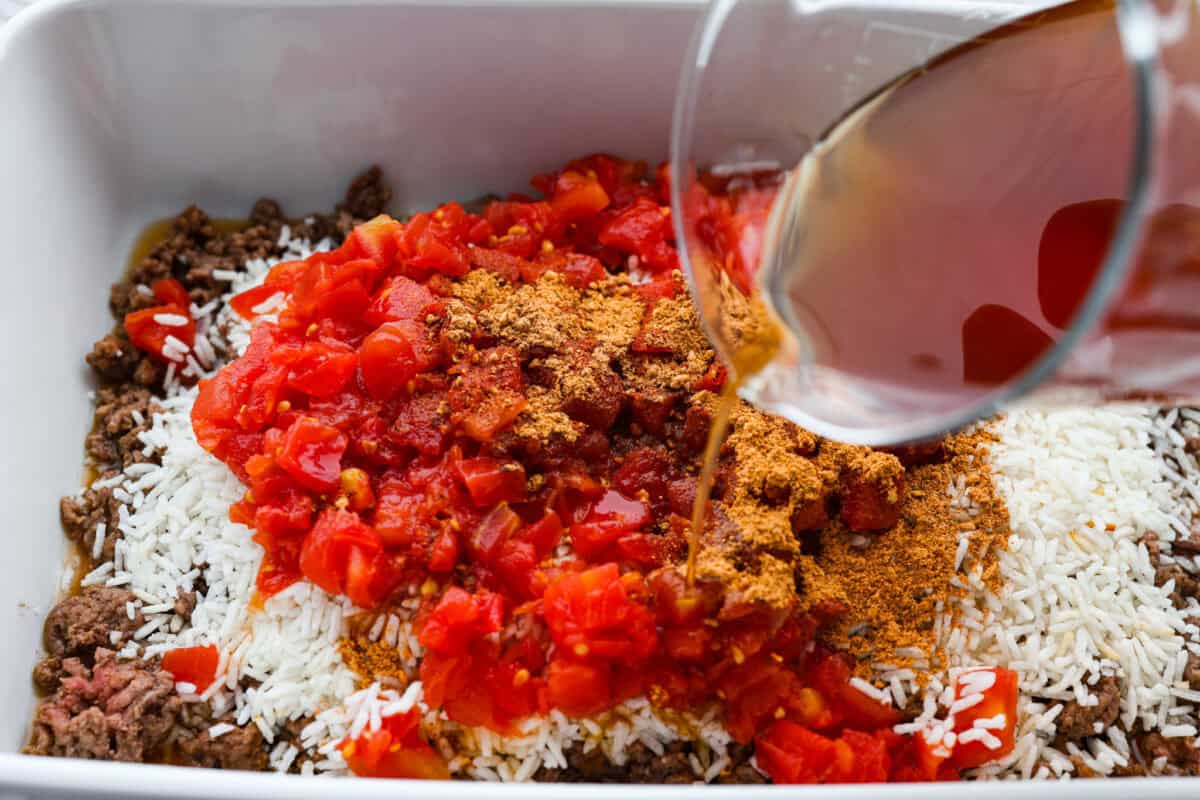 https://neuro-daily.report/homemade-bone-broth/ Someone pouring beef broth into the rice and beef mixture.