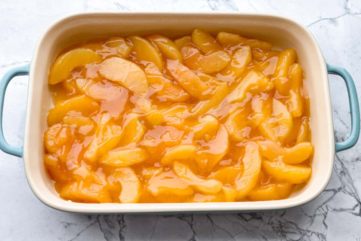This Apple Dump Cake is your new dessert BFF. You can just toss it together, pop it in the oven, and let the magic happen. Sweet, simple, and seriously so delicious. Baking dish with apple pie filling spread out on the bottom.