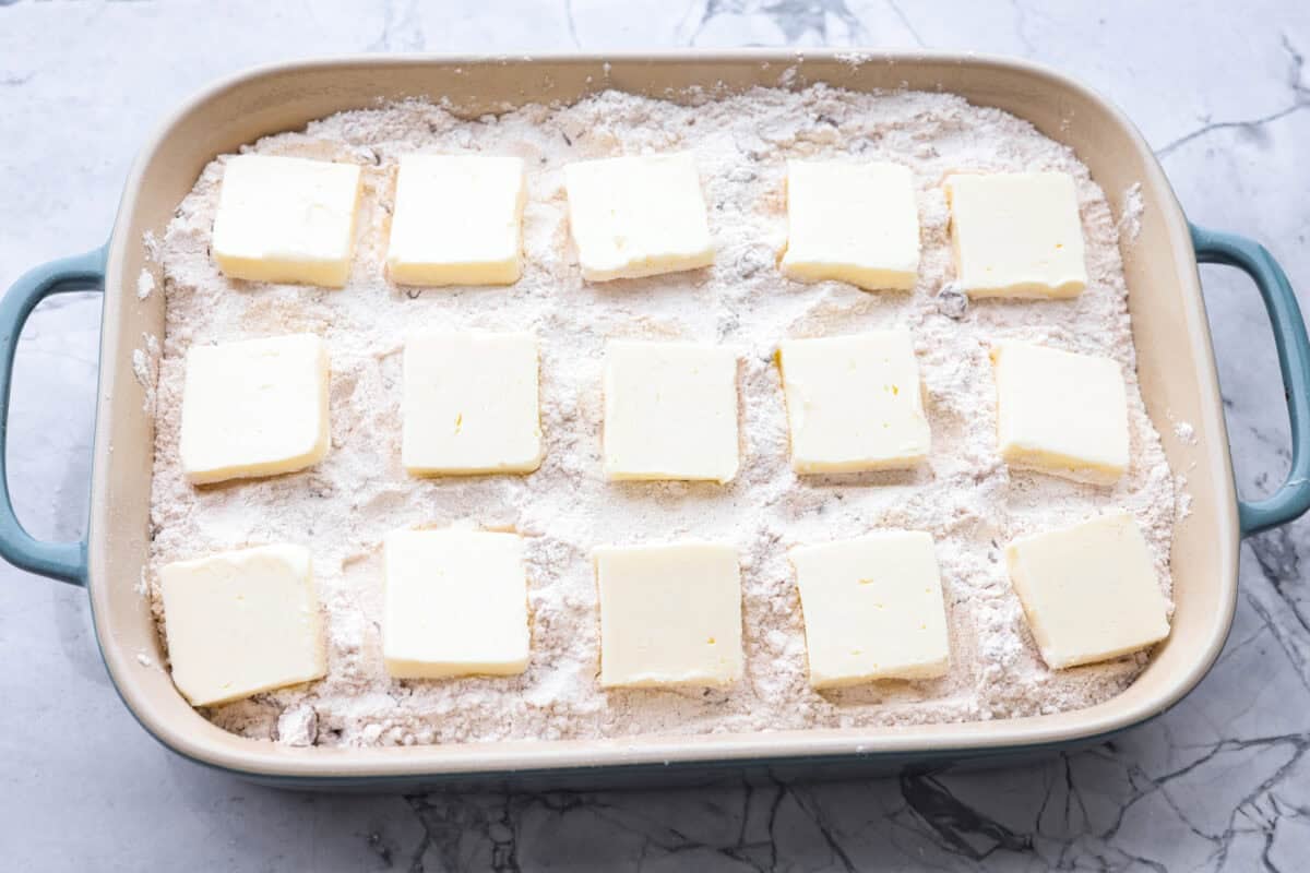 This Apple Dump Cake is your new dessert BFF. You can just toss it together, pop it in the oven, and let the magic happen. Sweet, simple, and seriously so delicious. Slices of butter spread out over the top of the cake mix mixture.