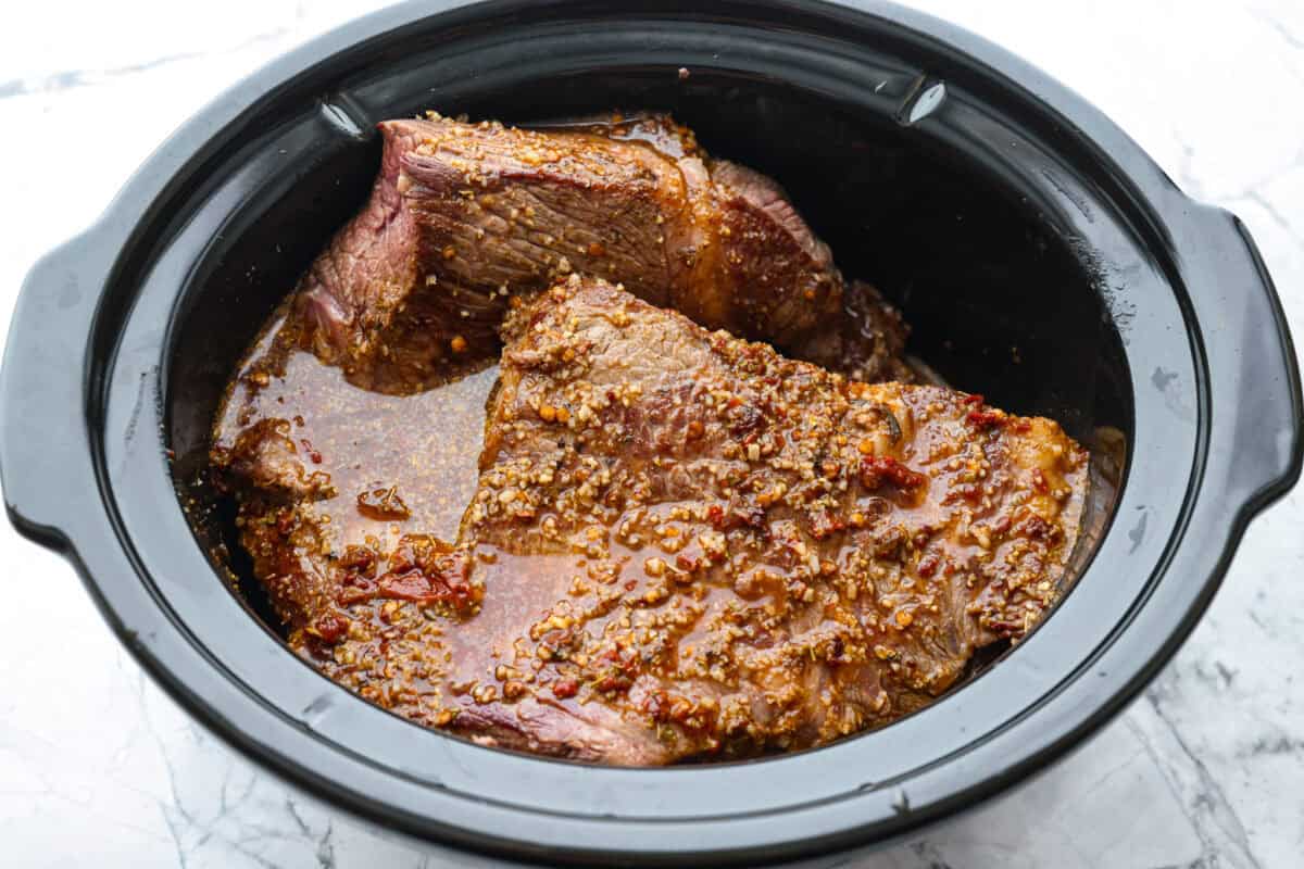Slow cooker barbacoa beef simmers all day in smoky chipotle, tangy lime, and warm spices until it falls apart. Itโs perfect for tacos, burritos, bowls, or nachos, all with that taquerรญa-style flavor at home. Sauce poured over the browned beef in the crockpot.