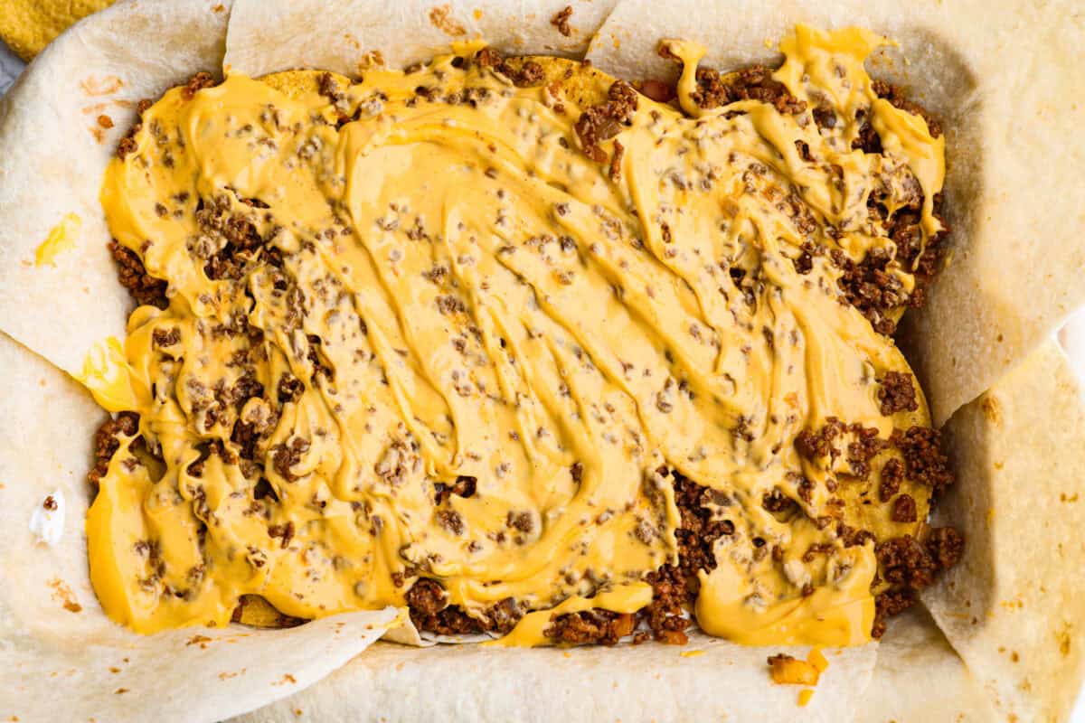 This TikTok-viral Crunchwrap Casserole takes Taco Bell’s iconic Crunchwrap Supreme and flips it into a cheesy, crunchy copycat casserole. It takes everything you love about the Crunchwrap and layers it into one big, family-sized dish! Nacho cheese layered and spread out over the top of the ground beef.
