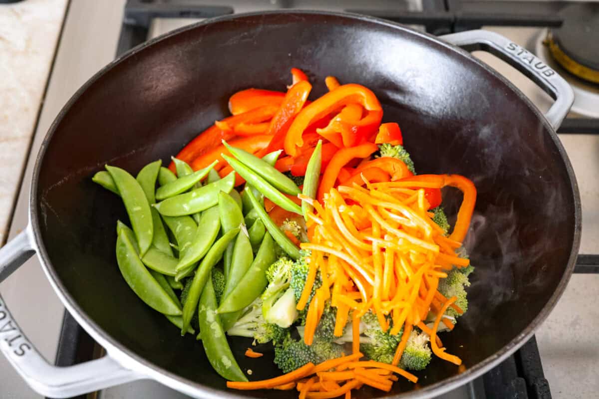 Some nights you just need dinner on the tableย fast! Thatโs when this garlic shrimp stir fry saves the day. Juicy shrimp, crisp veggies, and the BEST garlicky sauce all come together in 20 minutes. Veggies cut up and tossed in vegetable oil in a wok.