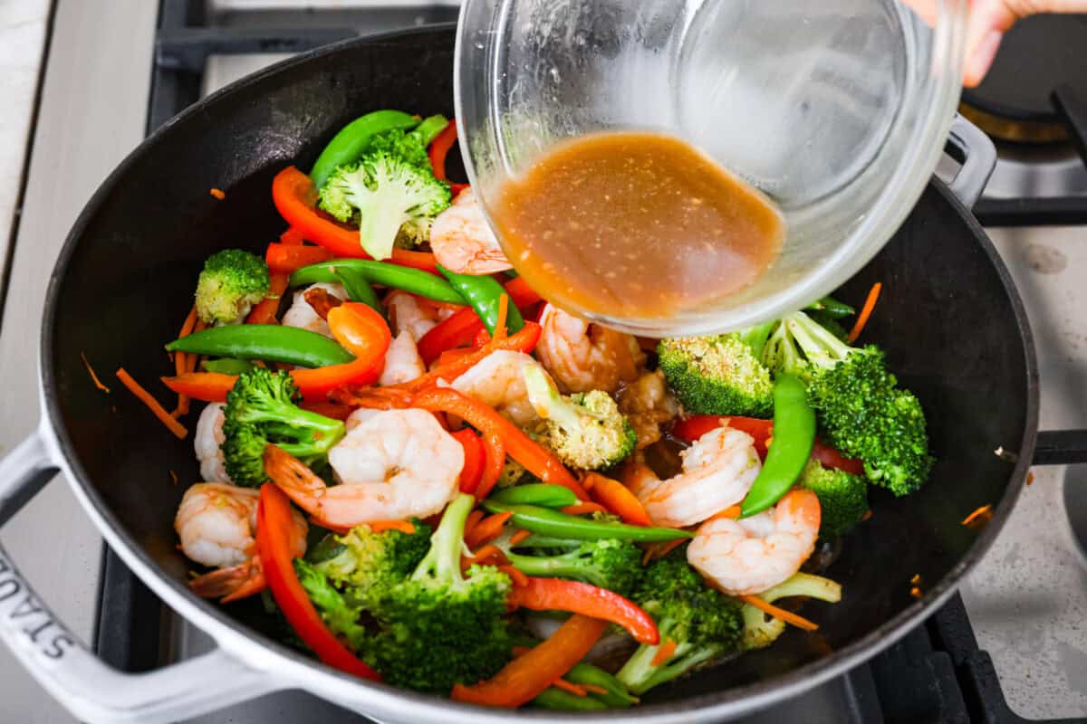 Some nights you just need dinner on the tableย fast! Thatโs when this garlic shrimp stir fry saves the day. Juicy shrimp, crisp veggies, and the BEST garlicky sauce all come together in 20 minutes. Garlic sauce poured over shrimp and veggies in the wok.