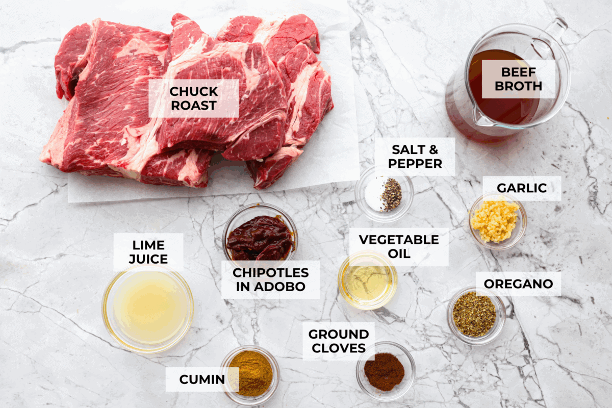 Slow cooker barbacoa beef simmers all day in smoky chipotle, tangy lime, and warm spices until it falls apart. Itโs perfect for tacos, burritos, bowls, or nachos, all with that taquerรญa-style flavor at home. Overhead shot of labeled ingredients.