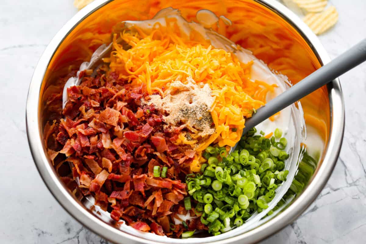 You need to stop what youโre doing and make this loaded baked potato dip right now! Itโs creamy, cheesy, bacony perfection! Itโs to die for. It's perfect for game day, parties, or to snack on while you catch up on your favorite show. Cheese, bacon, onions, garlic powder, salt, and pepper added to the cream cheese mixture.