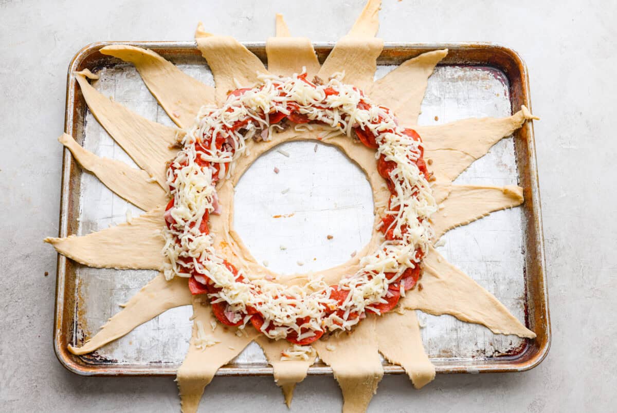 Pizza night just got a glow-up!ย This fun pull-apart pizza ring is perfect for family dinner, game day, or a party snack. Easy to make, endlessly customizable, and totally kid-approved, youโll be reaching for slice after slice! Cheese sprinkled over the top of the toppings.