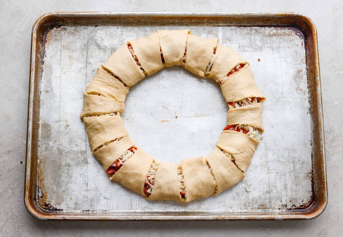 Pizza night just got a glow-up!ย This fun pull-apart pizza ring is perfect for family dinner, game day, or a party snack. Easy to make, endlessly customizable, and totally kid-approved, youโll be reaching for slice after slice! Each sunburst point of crescent dough folded over the toppings and cheese to create the pizza ring.