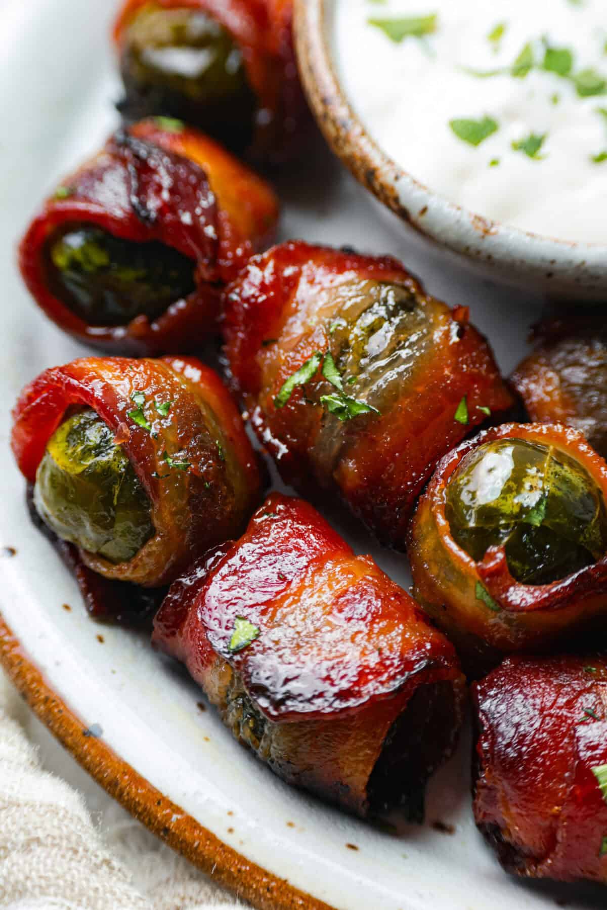 I love bacon. I love Brussels sprouts. Put them together and Iโm sold. But the secret to these bacon-wrapped Brussels sprouts? A drizzle of maple syrup! It makes them sweet, smoky, and completely irresistible. Close up shot of the bacon wrapped Brussels sprouts.