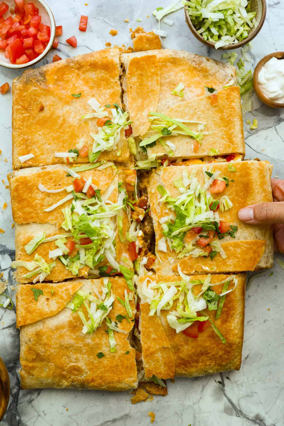 This TikTok-viral Crunchwrap Casserole takes Taco Bell’s iconic Crunchwrap Supreme and flips it into a cheesy, crunchy copycat casserole. It takes everything you love about the Crunchwrap and layers it into one big, family-sized dish! Overhead shot of crunchwrap casserole topped with shredded lettuce, tomatoes and cilantro.