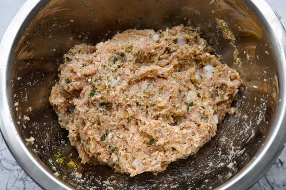 Meet your new favorite meatloaf! The ground chicken makes the Garlic Parmesan Chicken Meatloaf super moist, and you'll love the Parmesan herb-crusted topping! All of the meatloaf ingredients mixed together in a bowl.