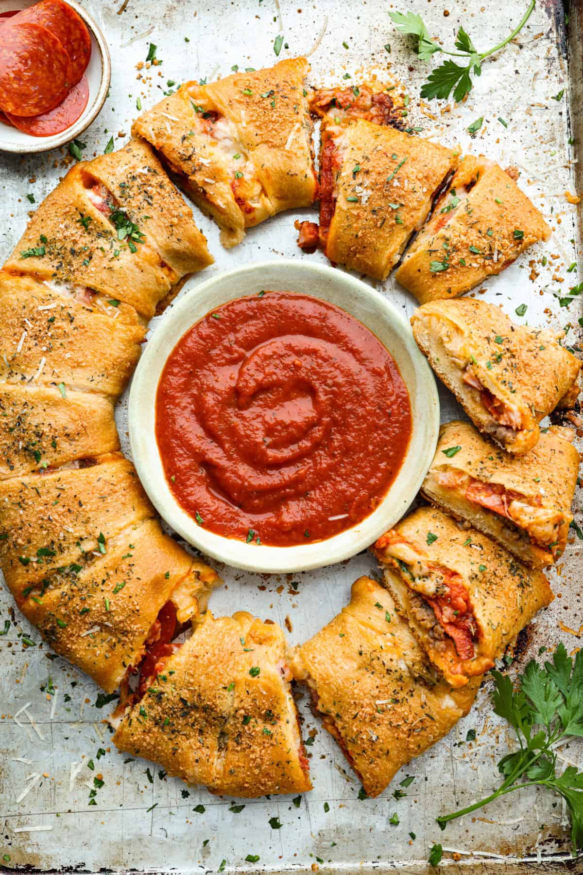 Pizza night just got a glow-up!ย This fun pull-apart pizza ring is perfect for family dinner, game day, or a party snack. Easy to make, endlessly customizable, and totally kid-approved, youโll be reaching for slice after slice! Overhead shot of the baked pizza ring with a bowl of marinara sauce in the middle.