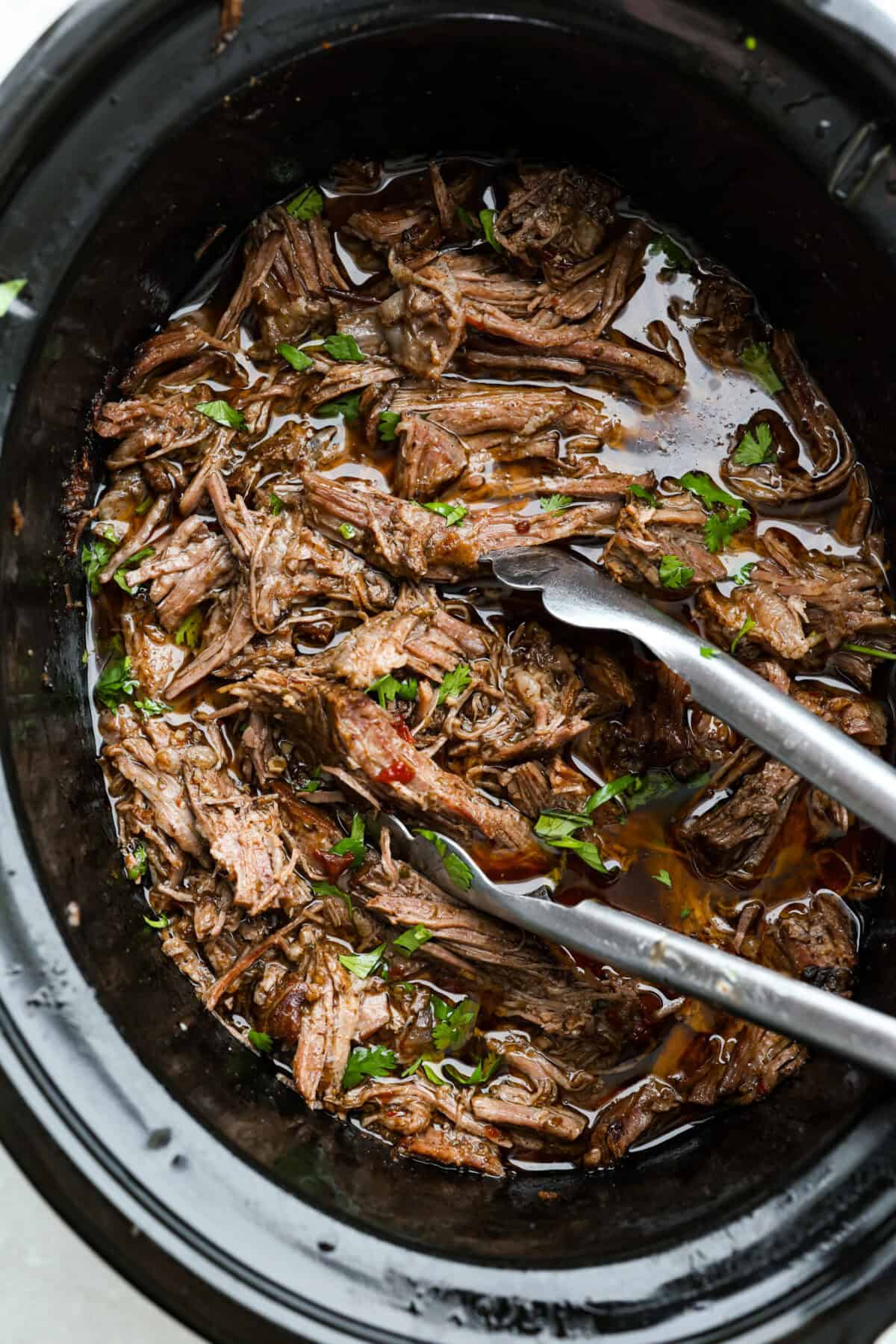 Slow cooker barbacoa beef simmers all day in smoky chipotle, tangy lime, and warm spices until it falls apart. Itโs perfect for tacos, burritos, bowls, or nachos, all with that taquerรญa-style flavor at home. Overhead shot of slow cooker Barbacoa beef still in the crockpot.
